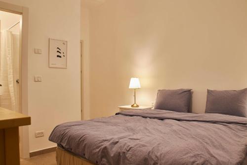 a bedroom with a bed and a lamp on a table at Roza Apartment in Tel Aviv