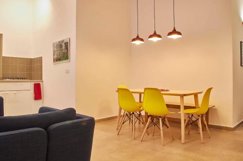 a dining room with a table and yellow chairs at Roza Apartment in Tel Aviv