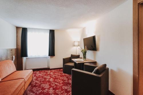 a hotel room with a couch and a chair at Hotel Adler in Warth am Arlberg