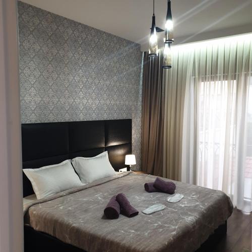 a bedroom with a large bed with purple slippers on it at Nova city center apartments in Tbilisi City