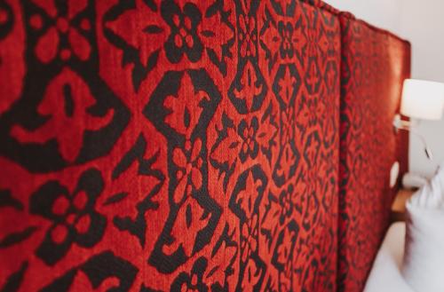 a red curtain with a black and red pattern on a bed at Hotel Adler in Warth am Arlberg