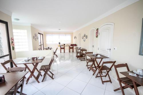 Suites Natalia Enseada في غوارويا: غرفة طعام مع طاولات وكراسي خشبية
