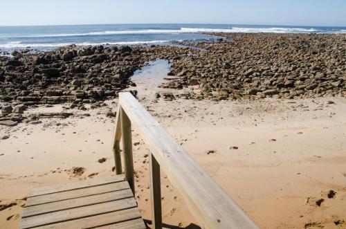 a wooden staircase leading to a beach with the ocean at Walter’s Place in Jongensfontein