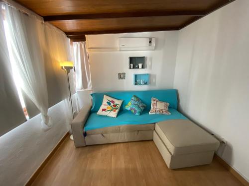 Habitación pequeña con sofá azul y ventana en Casa Céntrica con Wifi Gratis, en Almuñécar