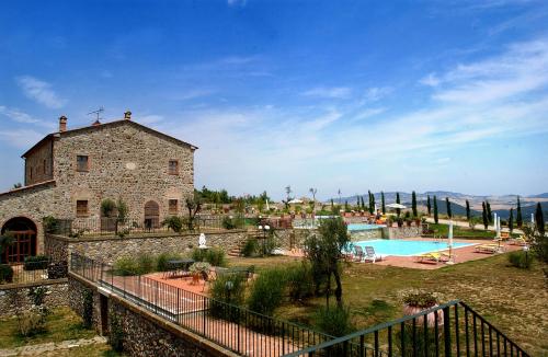 a building and a swimming pool in a yard at Relais Poggio al Vento in Pomarance