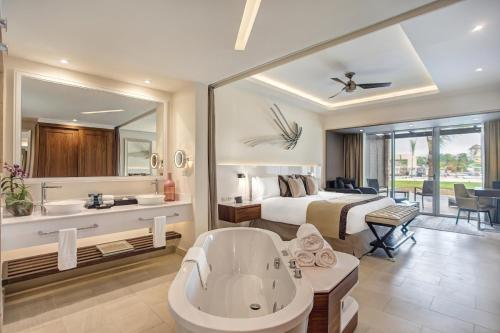 ein Hotelzimmer mit einer Badewanne und einem Bett in der Unterkunft Royalton Blue Waters Montego Bay, An Autograph Collection All-Inclusive Resort in Falmouth