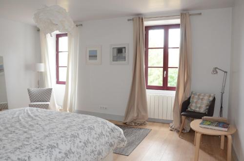a bedroom with a bed and a chair and windows at Gite La Maison Blanche Familiale Château La Roche Racan in Saint-Paterne-Racan
