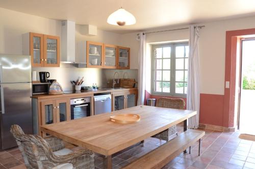 une cuisine avec une table en bois et un réfrigérateur dans l'établissement Gite Familial Chateau La Roche Racan, à Saint-Paterne-Racan
