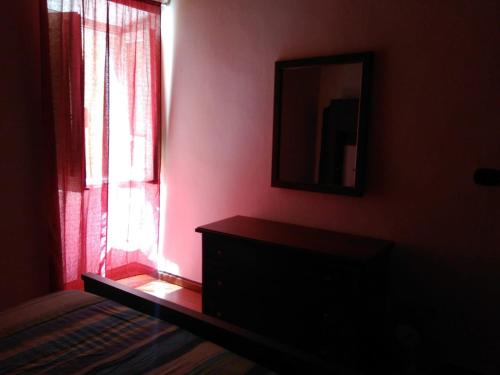 a room with a window and a dresser and a mirror at Ca Rosella in Sorso