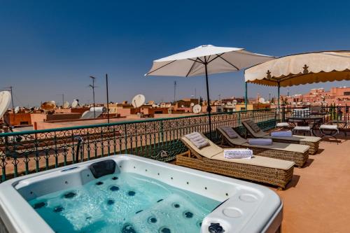 a hot tub on a balcony with chairs and umbrellas at Villa Soraya Hammam & Jacuzzi in Marrakesh