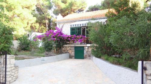 a small house with a green door and purple flowers at Holiday Home Dragan - 50m from sea in Splitska