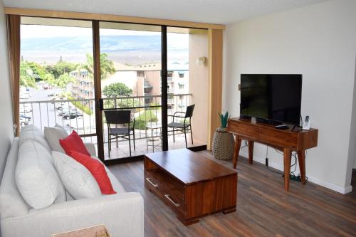 a living room with a white couch and a flat screen tv at Pacific Shores A406 in Kihei