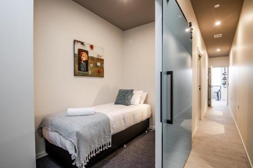 a small bedroom with a bed and a hallway at Central city apartment in Launceston
