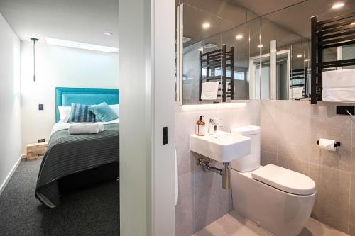 a bathroom with a sink and a toilet and a bed at Central city apartment in Launceston