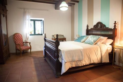 a bedroom with a large bed and a chair at Casa Rural Priorato San Martín in Amés