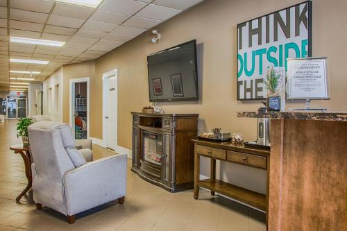a waiting room with a chair and a desk and a tv at Northwood Plaza Hotel in Prince George