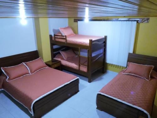 a room with two beds and a desk in it at Hotel El Cangrejo in Paipa