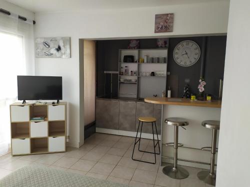 cocina con barra con taburetes y TV en Fleur d'orchidée studio 99 en Sens