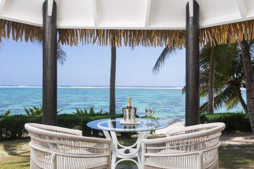 a table and chairs with the ocean in the background at Motu Beachfront Art Villas in Rarotonga