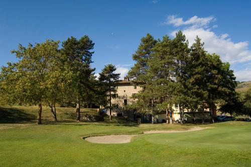 a golf course with trees and a building in the background at Lodole B&B in Monzuno