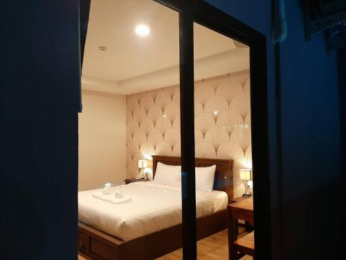a bedroom with a bed and a mirror at J.P.GRAND HOTEL in Trat