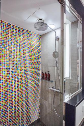 a bathroom with a shower with a colorful tiled wall at The Royal Park Canvas - Osaka Kitahama in Osaka