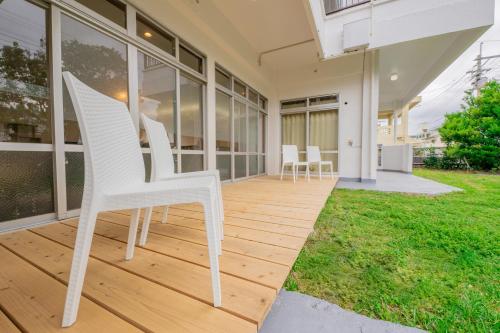 a white chair sitting on a porch of a house at パライソ デ モトブ in Motobu