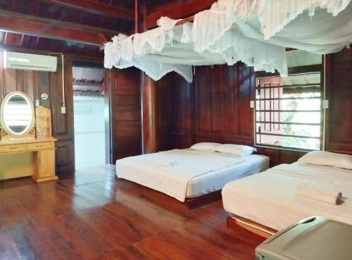 two beds in a room with wooden walls and wood floors at Green Hope Lodge in Cat Tien