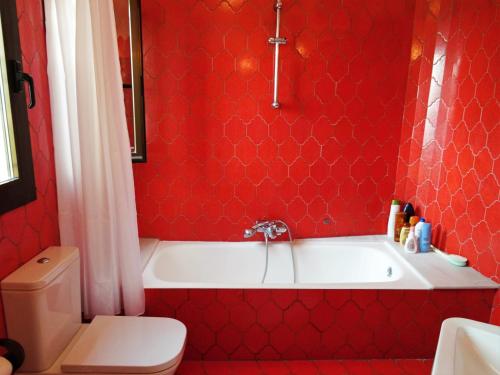 baño rojo con bañera blanca y aseo en Casa Kirbo, en Altea