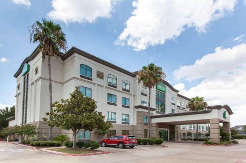 a building with a red car parked in front of it at Wingate By Wyndham Houston / Willowbrook in Houston