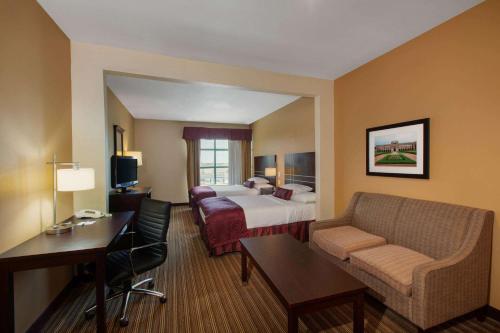 a hotel room with a bed and a couch at Wingate By Wyndham Houston / Willowbrook in Houston
