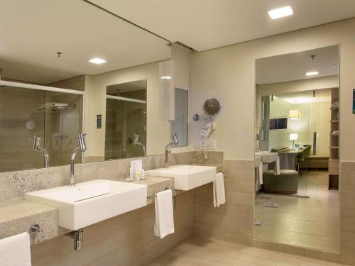 a bathroom with two sinks and a large mirror at Mercure Salvador Rio Vermelho in Salvador