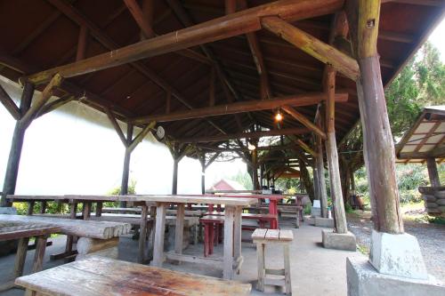 a group of wooden tables and benches in a pavilion at Gokase Campsite Camping and Guesthouse in Gokase
