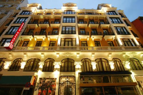 a large white building with a red sign on it at Petit Palace Chueca in Madrid