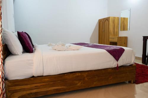 a bedroom with a bed with white sheets and purple pillows at Pine Tree Munnar in Munnar