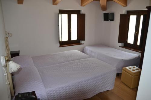 two beds in a room with two windows at Agriturismo Antico Muro in Sassoferrato