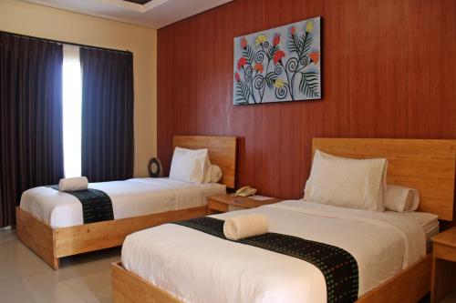 a hotel room with two beds and a picture on the wall at Exotic Komodo Hotel in Labuan Bajo