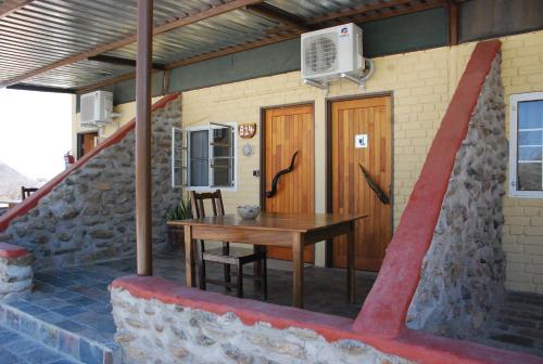 a house with a wooden table and a wooden door at Oppi-Koppi Rest Camp in Kamanjab