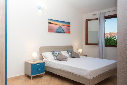 a bedroom with a bed with a blue nightstand and a window at villette acquamarina Budoni in Budoni