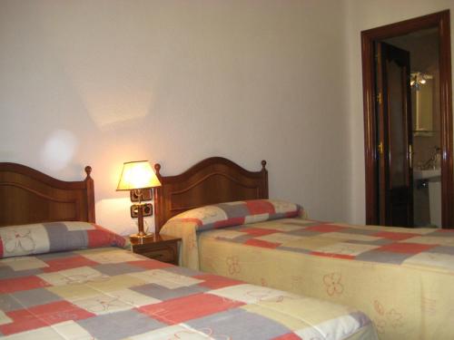 Hostal Los Andes في مدريد: غرفة نوم بسريرين ومصباح على طاولة