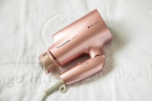 a pink bottle of hair drier on a bed at Orange Inn Sendaihigashi in Sendai
