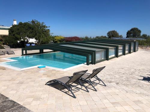 une paire de chaises et une piscine dans l'établissement I Trulli della NaturaBio, à Martina Franca