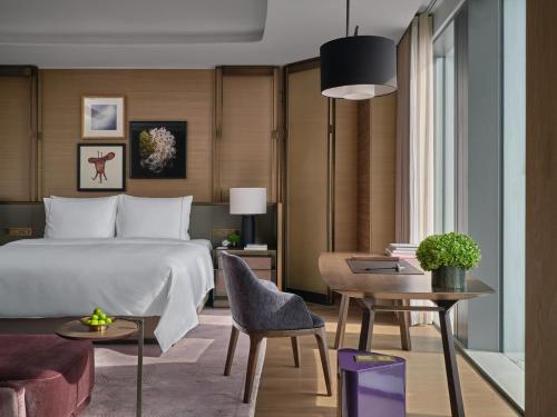 a bedroom with a bed and a table with a chair at Rosewood Guangzhou, enjoy free shuttle bus service between the hotel and the Canton Fair Complex during the Canton Fair in Guangzhou
