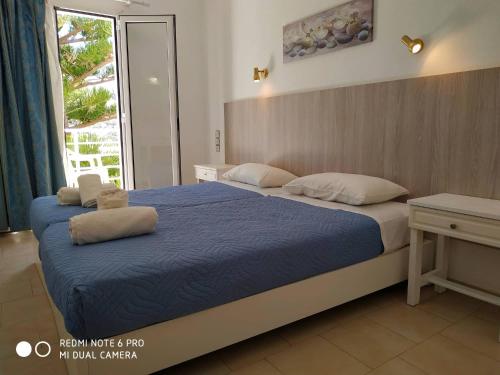 a bedroom with two beds with blue sheets and a window at Marina Hotel in Matala