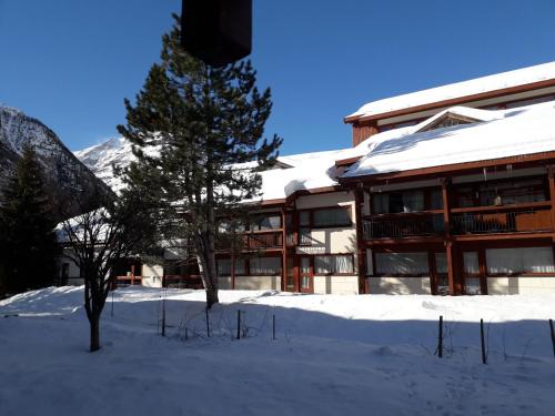 a snow covered building with a tree in front of it at Studio 4 personnes équipé wifi in Bessans