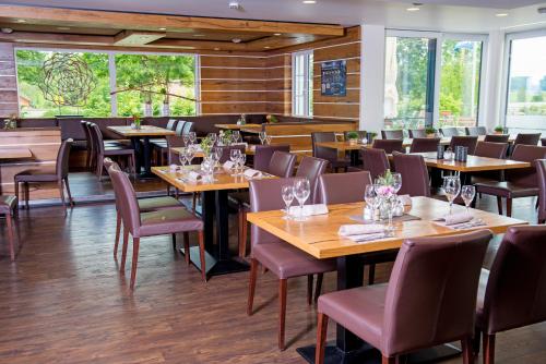 a restaurant with wooden tables and chairs and windows at Truschwende 4 in Bad Wurzach