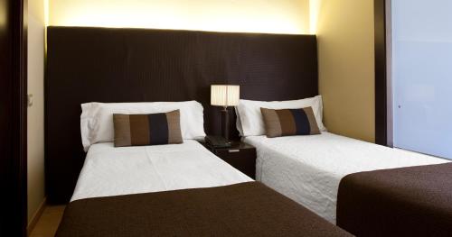 une chambre d'hôtel avec deux lits et une lampe dans l'établissement Senator Barcelona Apartments, à Barcelone