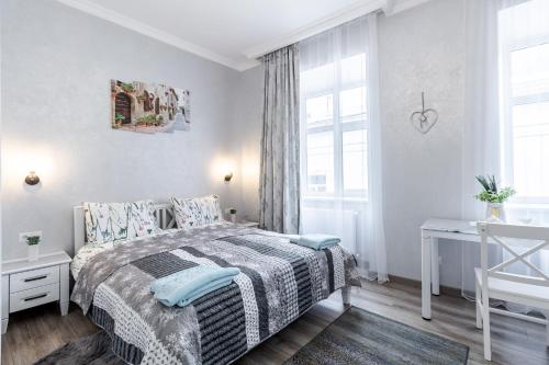 a white bedroom with a bed and a desk at Golden Rose ! Apartments Lviv in Lviv