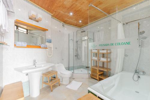 a bathroom with a sink and a toilet and a tub at Pousada de Coloane Boutique Hotel in Macau