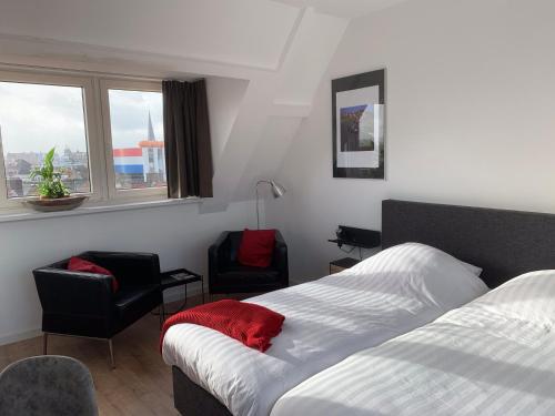 a bedroom with a bed and two chairs and a window at Bij Frits in Zandvoort